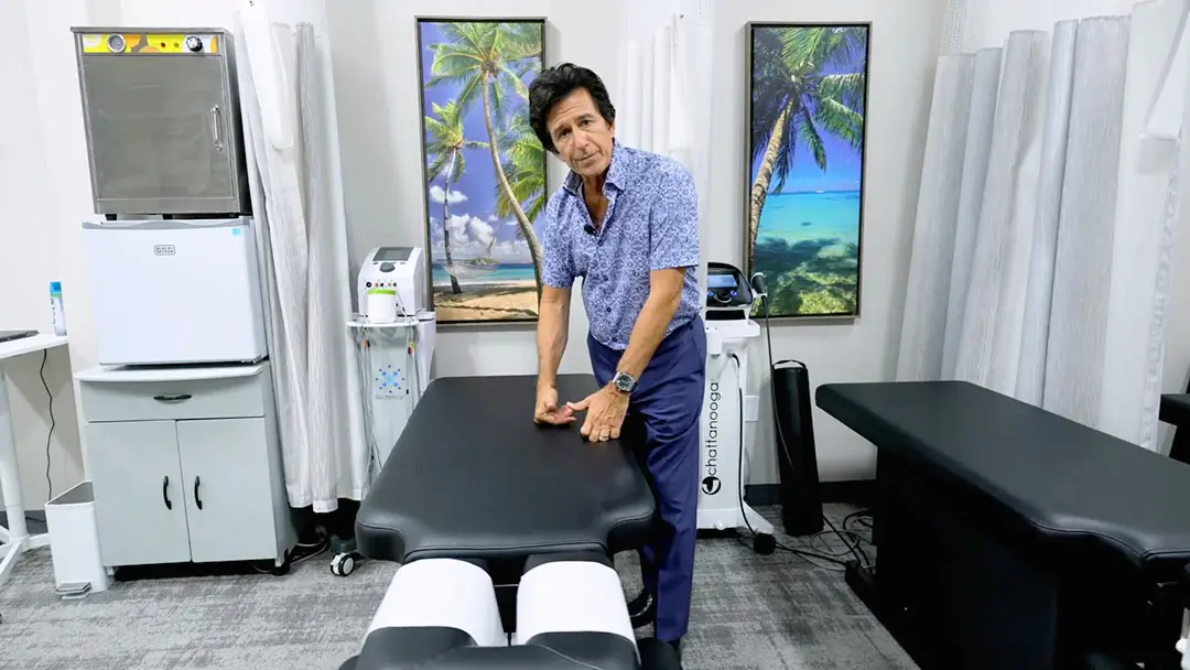 Dr. Ivan demonstrating manual therapy techniques on a specialized chiropractic adjustment table at Novare Injury Care.