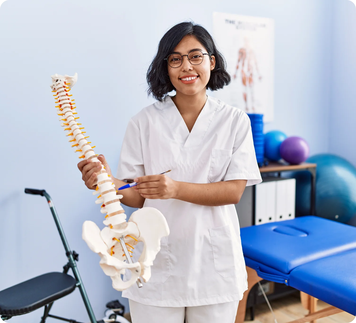 A medical professional holding a full spinal column model to explain disc pain and spinal health to a patient at Novare Injury Care.