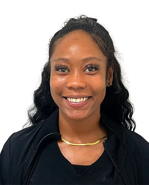 Smiling female healthcare provider with long dark hair wearing gold necklace from Novare Injury Care Fort Myers.